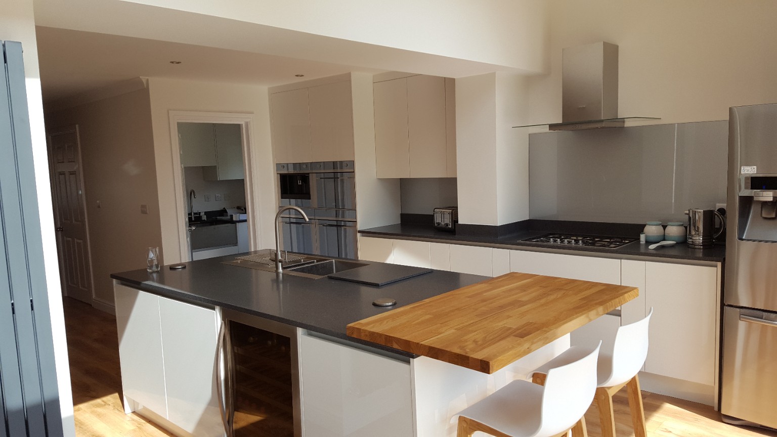 Kitchen fitted by RCB with white cabinetry, a dark island worktop and timber breakfast bar